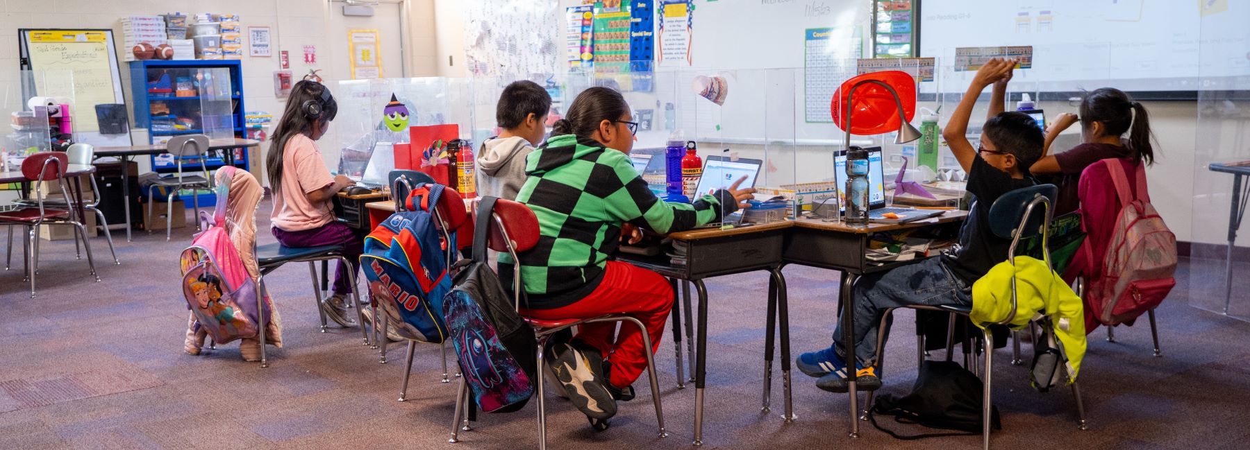 A group of students sitting at desks in a bright classroom, focused on their work and enjoying learning together.